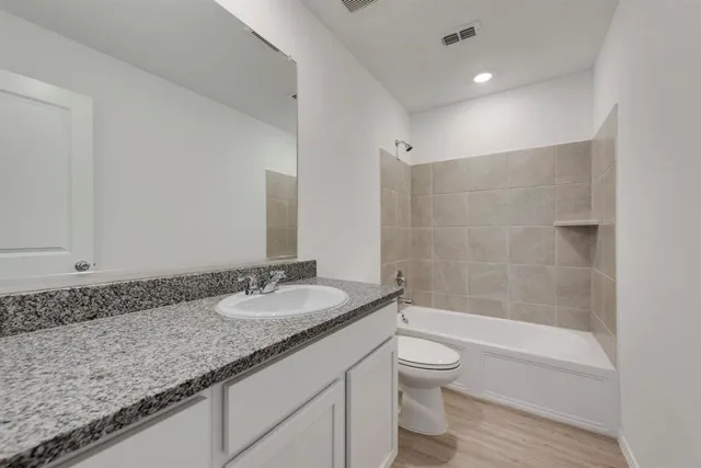 a bathroom with a granite countertop sink a toilet and shower