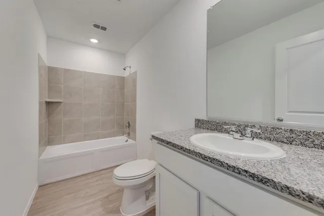 a bathroom with a granite countertop sink a toilet and shower