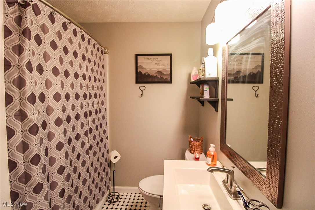 3267 South Leavitt Road Southwest Warren, OH 44481 - Photo 22 of 45 Bathroom with a shower with curtain, tile patterned flooring, vanity, and a textured ceiling