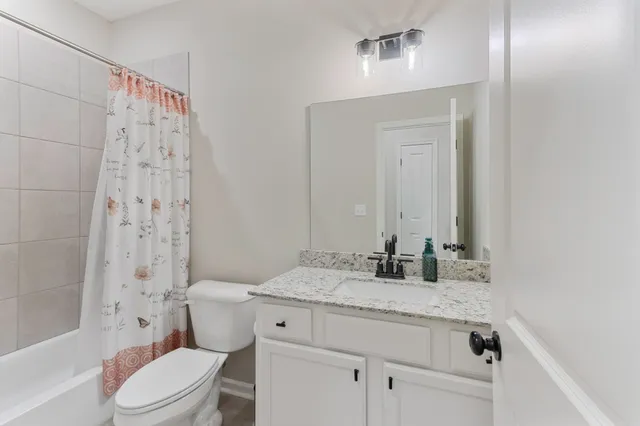 a bathroom with a granite countertop sink a toilet and shower