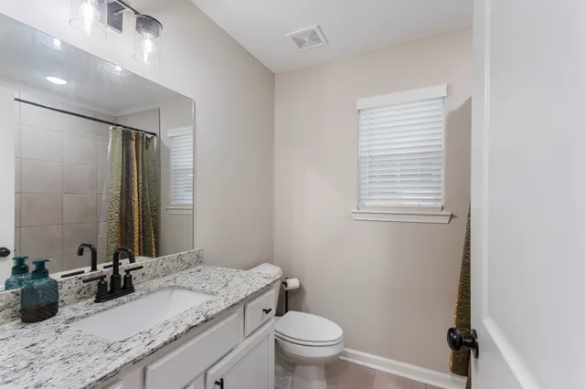a bathroom with a granite countertop sink toilet and mirror