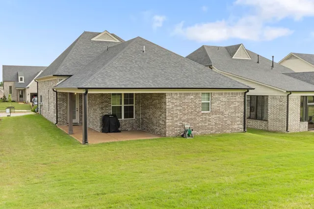 a view of a house with a yard and a large tree
