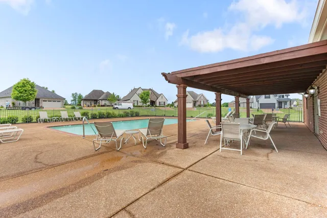 a view of a patio with a table and chairs under an umbrella with a barbeque