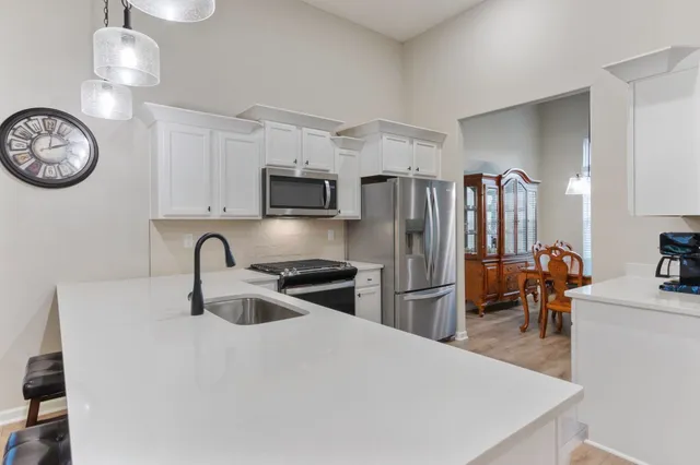 a kitchen with stainless steel appliances granite countertop a refrigerator a stove a sink a oven a dining table and chairs