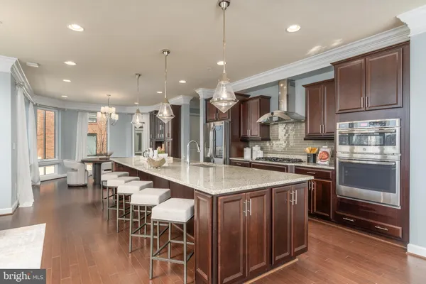 a dining room with wooden floor a chandelier a glass table and chairs