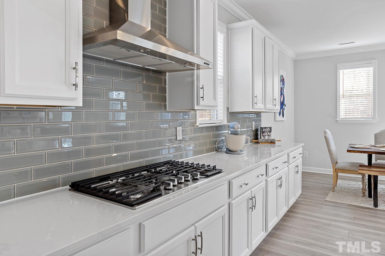 1445 Commons Ford Place Apex, NC 27539 - Photo 6 of 34 a kitchen with stainless steel appliances a stove a sink and white cabinets