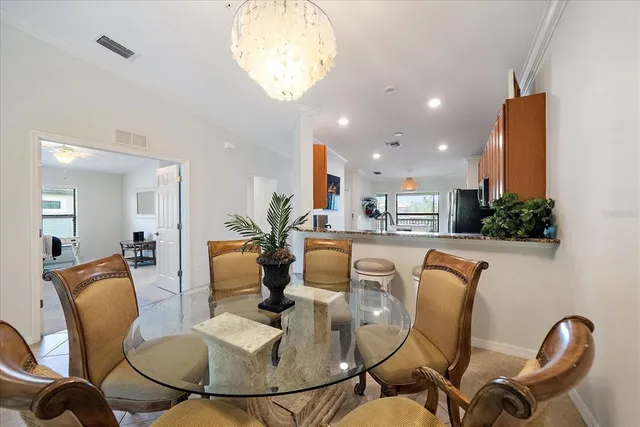 a dining room with furniture a chandelier and kitchen view