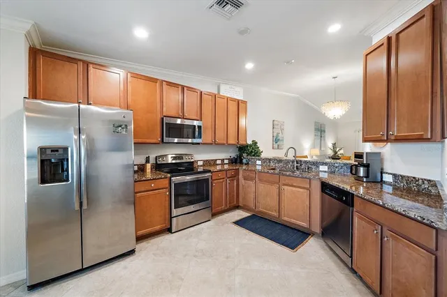 a large kitchen with stainless steel appliances granite countertop a refrigerator a sink dishwasher a stove and a refrigerator