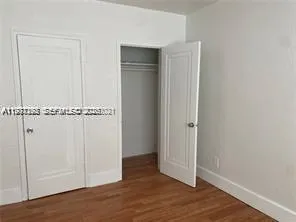 an empty room with wooden floor and closet