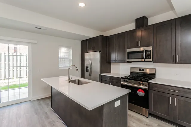 a kitchen with a refrigerator a sink a stove a microwave and wooden cabinets