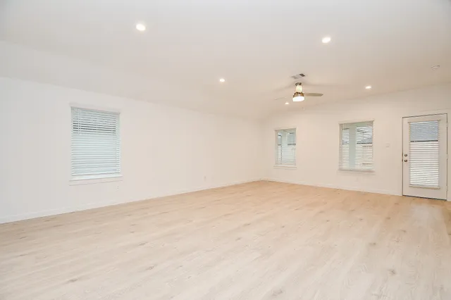 an empty room with a window and ceiling fan