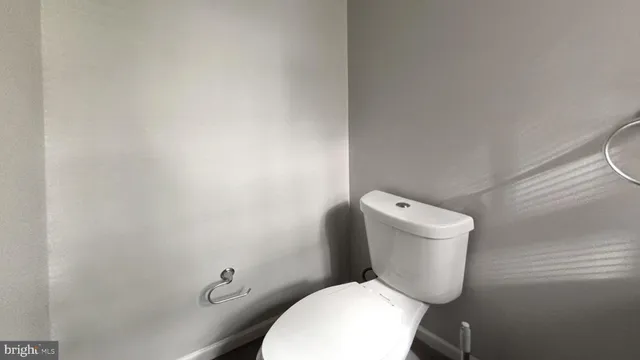 a white toilet sitting next to a white wall