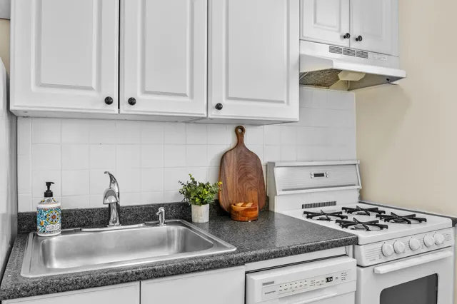 a kitchen with granite countertop a sink stainless steel appliances and cabinets