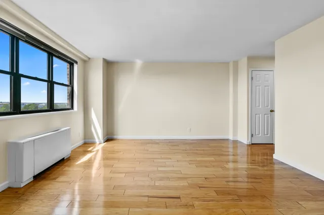 a view of an empty room with window and wooden floor