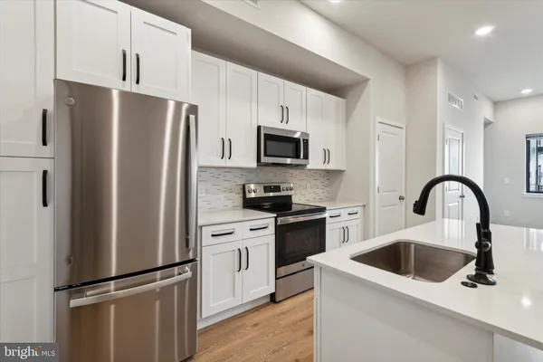 a kitchen with stainless steel appliances a refrigerator sink and microwave