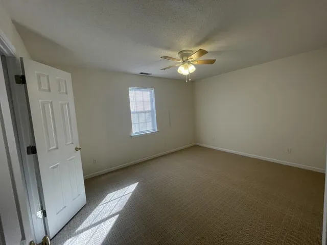 an empty room with a window and a fan