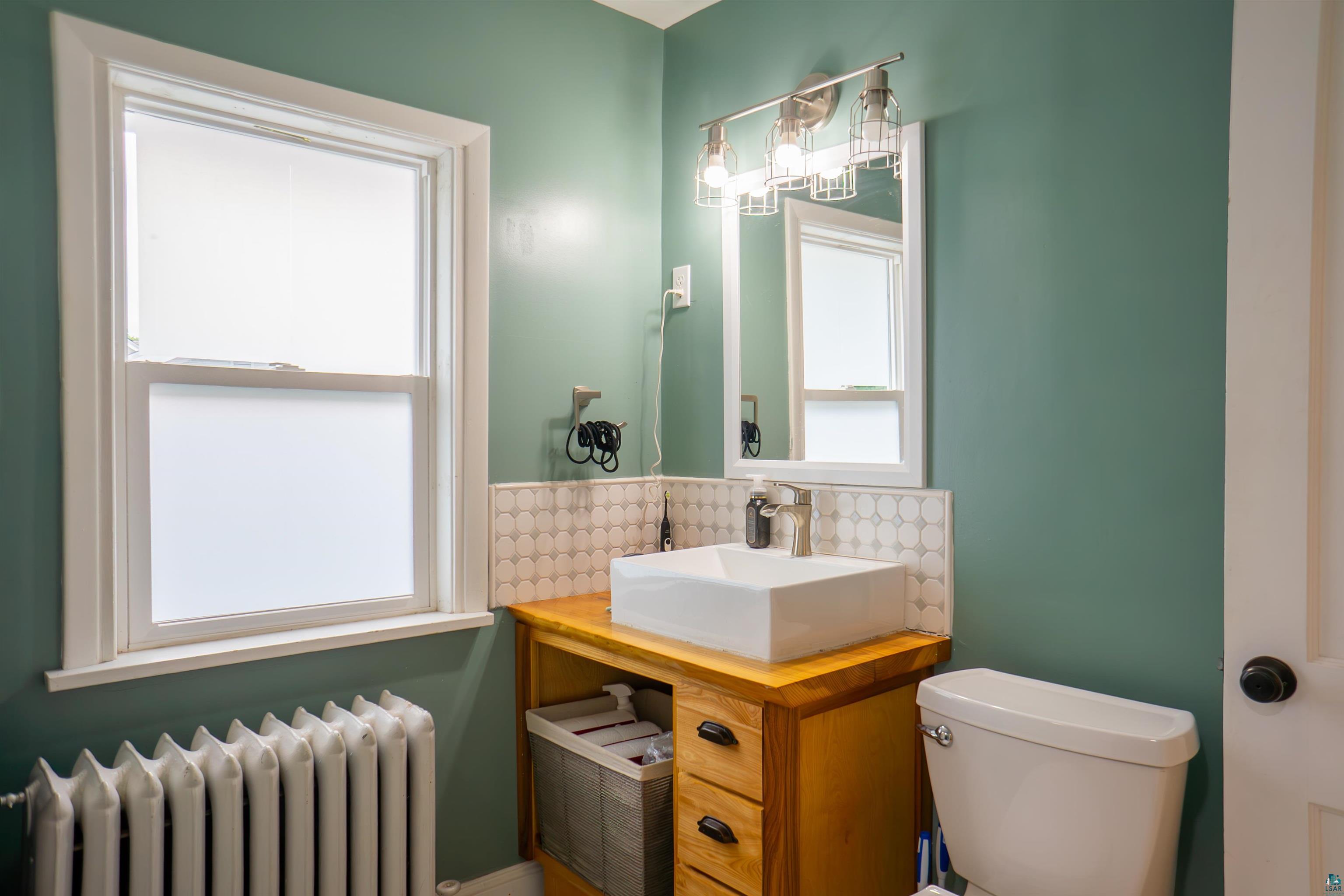 201 Snively Road Duluth, MN 55803 - Photo 12 of 21 Bathroom with vanity, radiator heating unit, decorative backsplash, and toilet