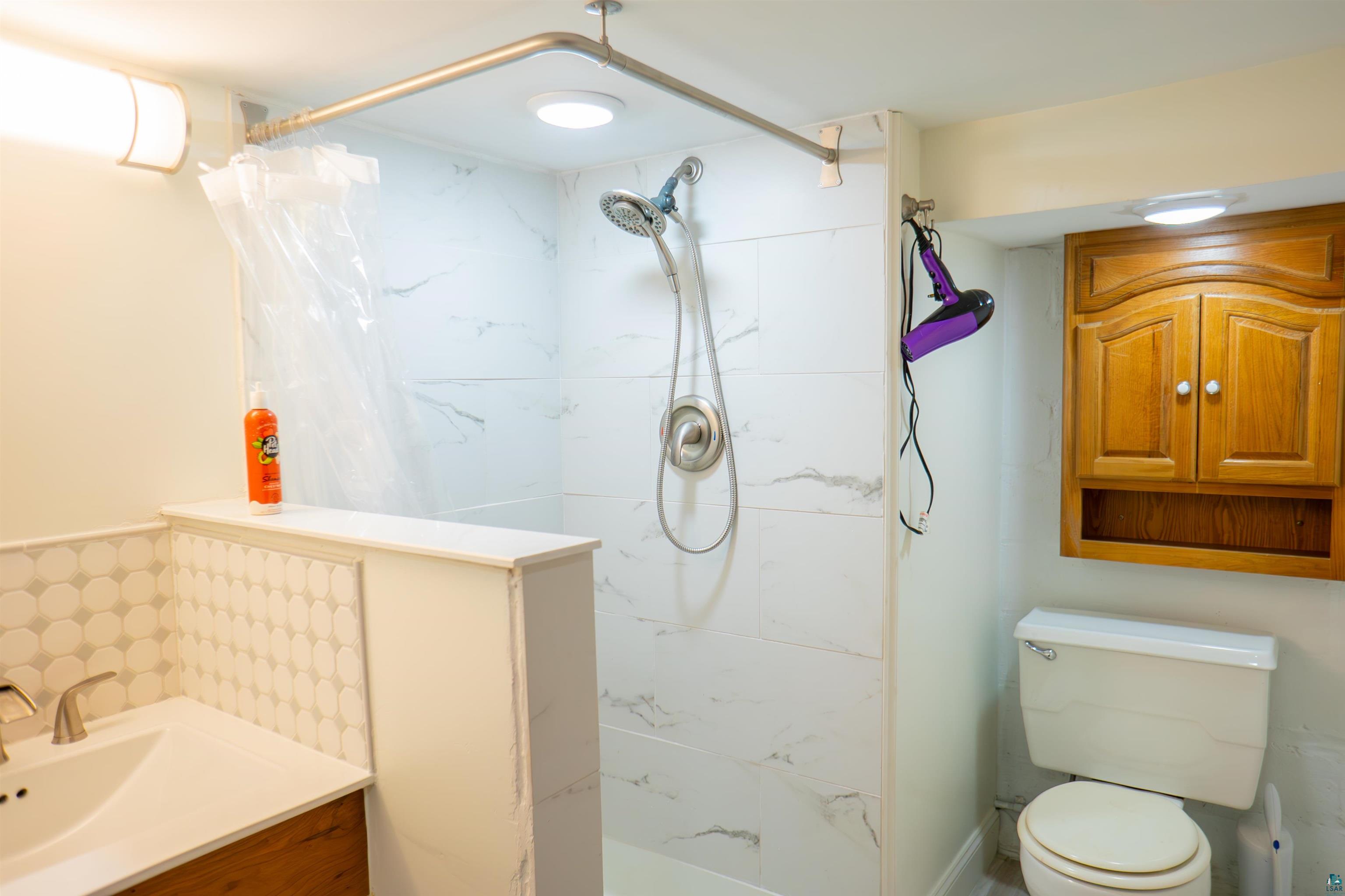 201 Snively Road Duluth, MN 55803 - Photo 17 of 21 Bathroom featuring vanity, walk in shower, and toilet