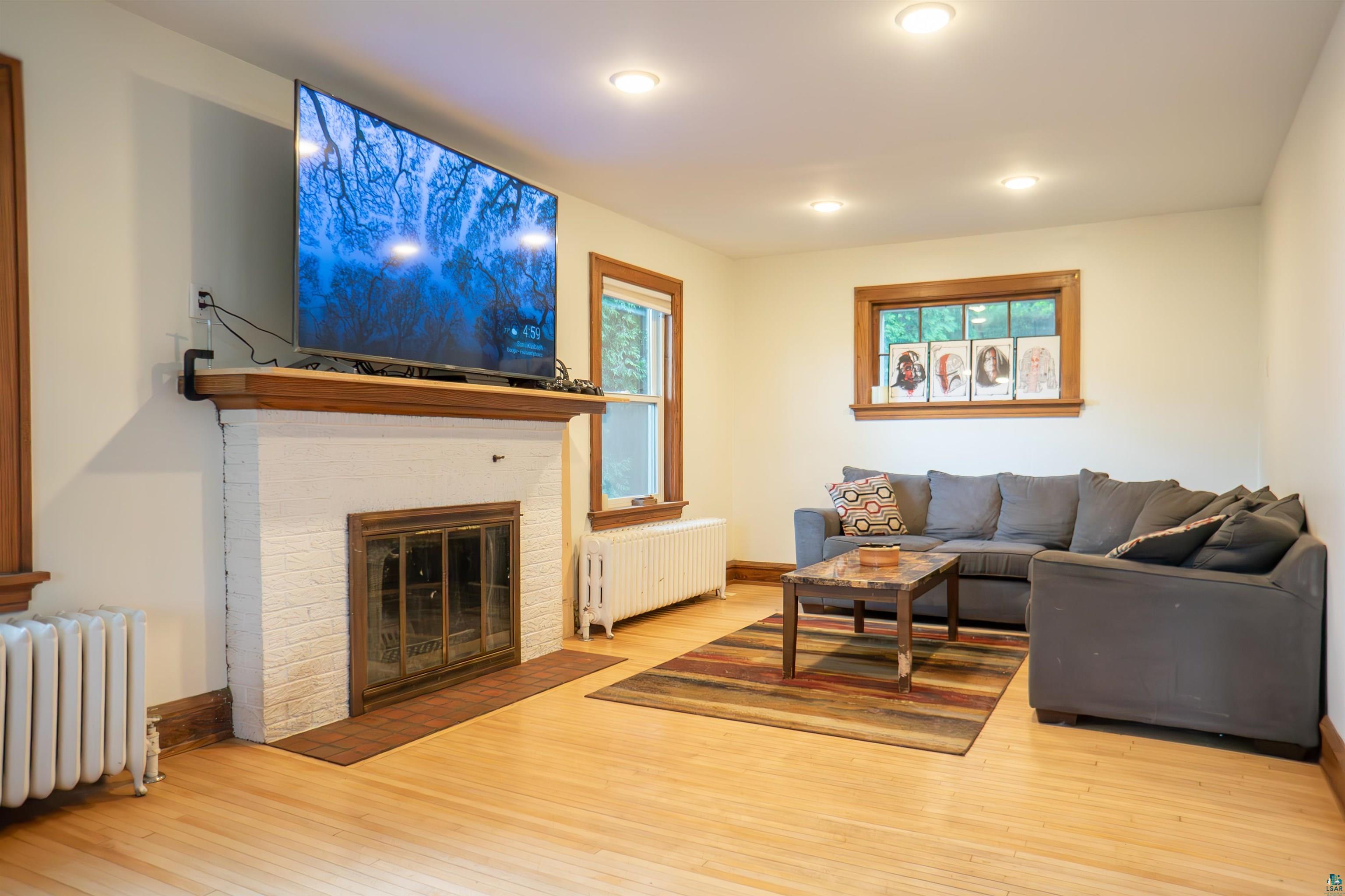 201 Snively Road Duluth, MN 55803 - Photo 5 of 21 Living room with a fireplace, radiator, and light wood-type flooring