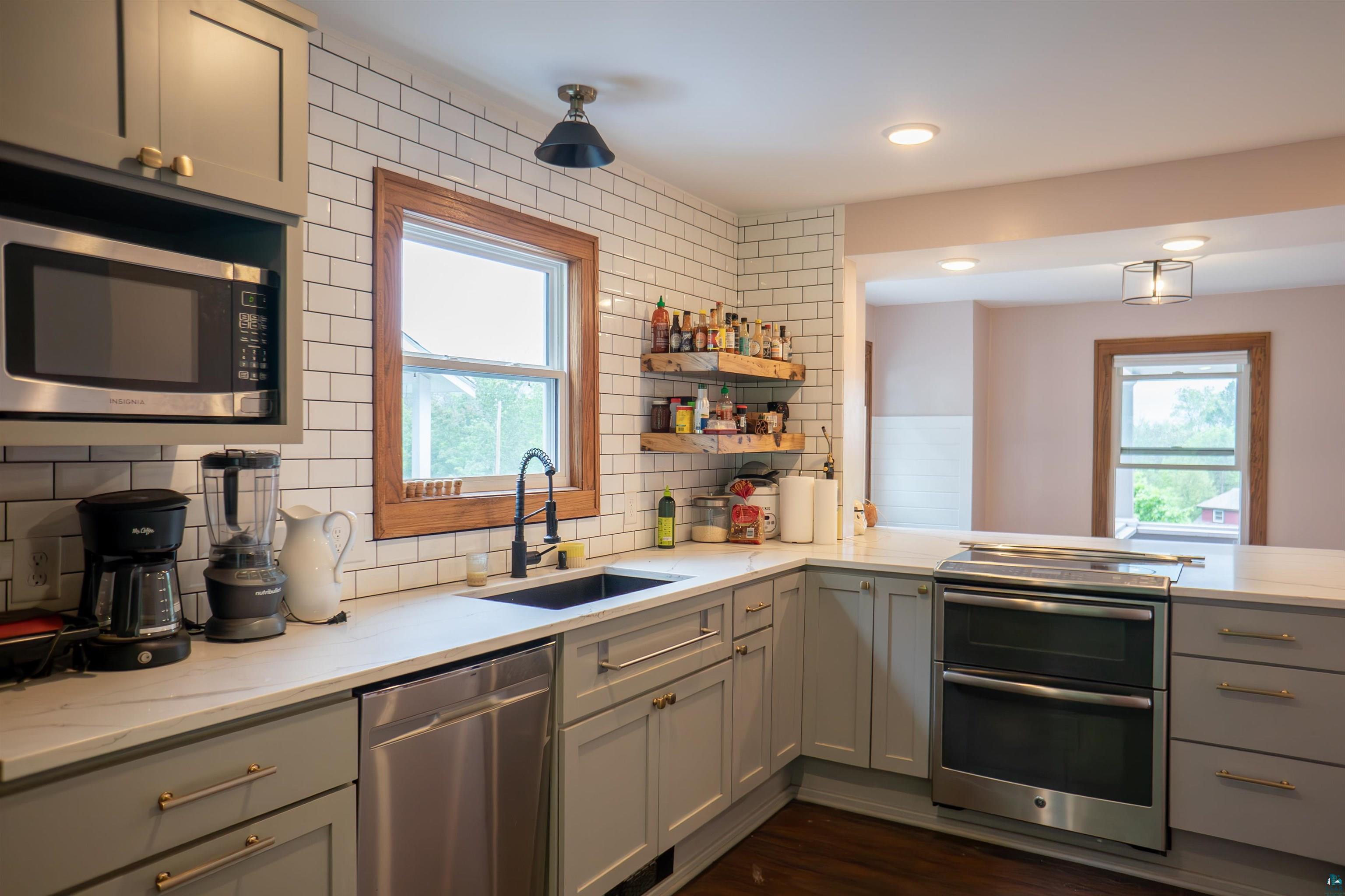 201 Snively Road Duluth, MN 55803 - Photo 9 of 21 Kitchen featuring sink, a wealth of natural light, decorative backsplash, and stainless steel appliances