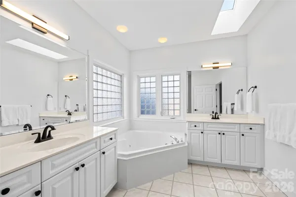 a bathroom with a sink double vanity granite tub shower and a mirror