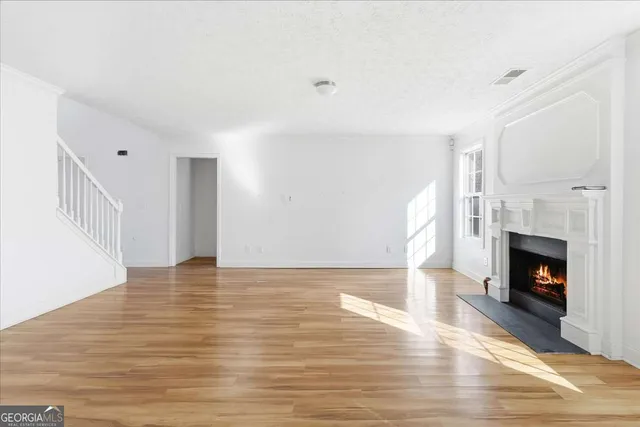 a view of an empty room with wooden floor fireplace and a window