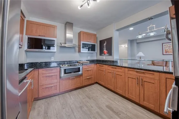 a kitchen with stainless steel appliances granite countertop wooden cabinets a microwave a sink and a counter