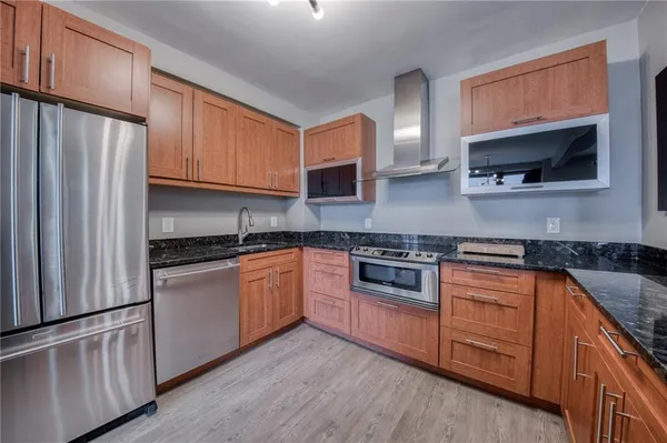 a kitchen with stainless steel appliances granite countertop a refrigerator a stove top oven a sink and dishwasher