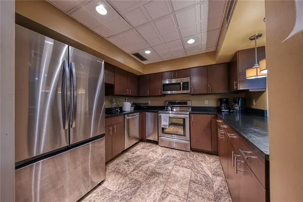 a kitchen with stainless steel appliances granite countertop a refrigerator a stove a sink and a microwave