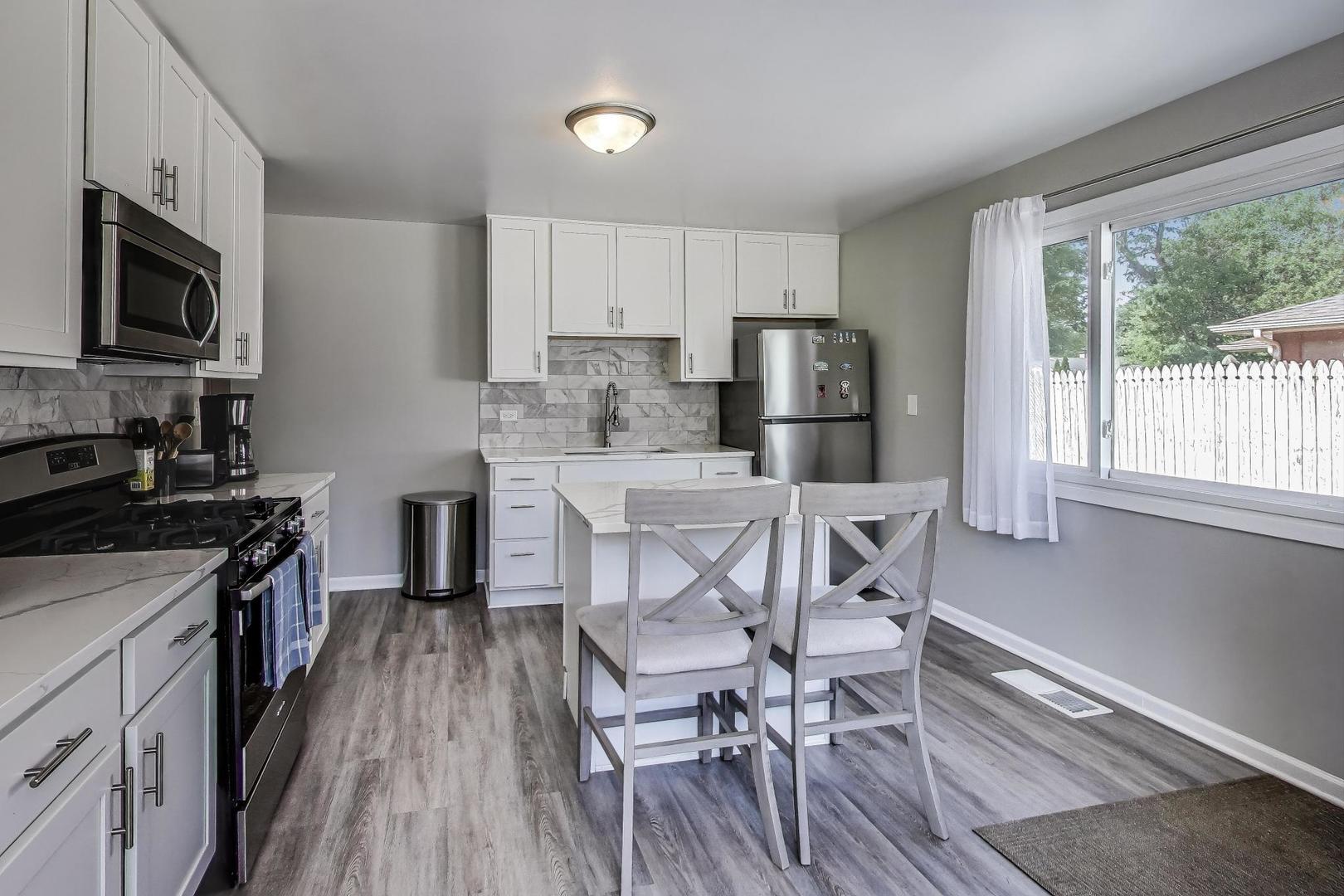 3600 Owl Drive Rolling Meadows, IL 60008 - Photo 7 of 21 a kitchen with stainless steel appliances granite countertop a stove top oven a sink dishwasher a dining table and chairs with wooden floor
