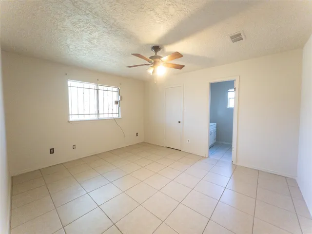 an empty room with chandelier fan and windows