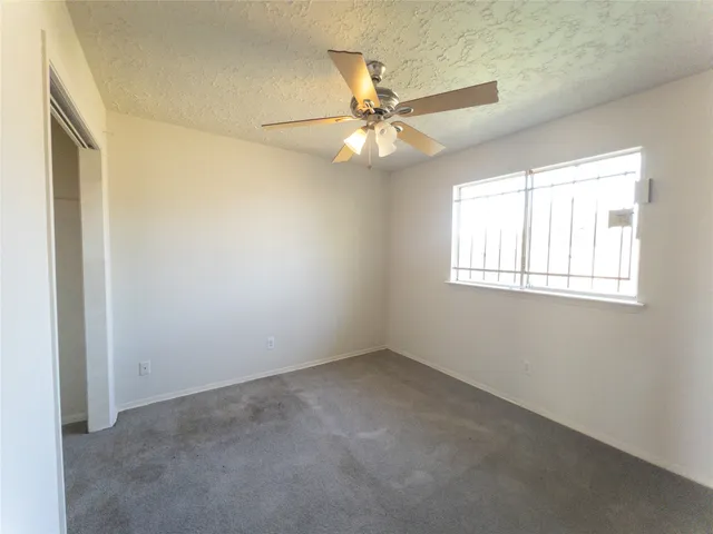 an empty room with windows and fan