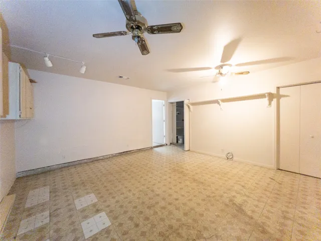 an empty room with ceiling fan and windows