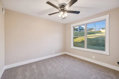 an empty room with chandelier fan