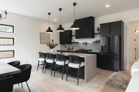 a kitchen with stainless steel appliances granite countertop a refrigerator a sink a stove a dining table and chairs