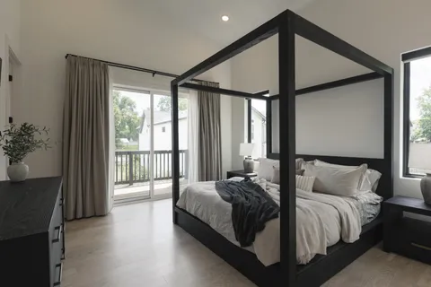 a bedroom with a bed two lamps and a large mirror