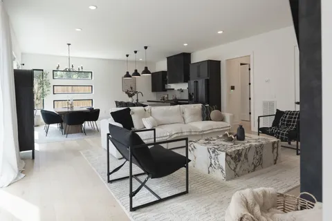 a living room with furniture a rug kitchen view and a window