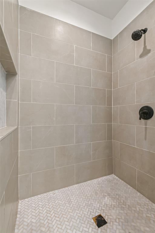 120 Long Ranger Road Abilene, TX 79602 - Photo 15 of 23 Shower stall featuring large format gray wall tiling, herringbone pattern floor tiling, a built-in shower niche, and matte black fixtures