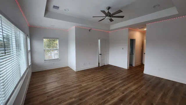an empty room with wooden floor and windows