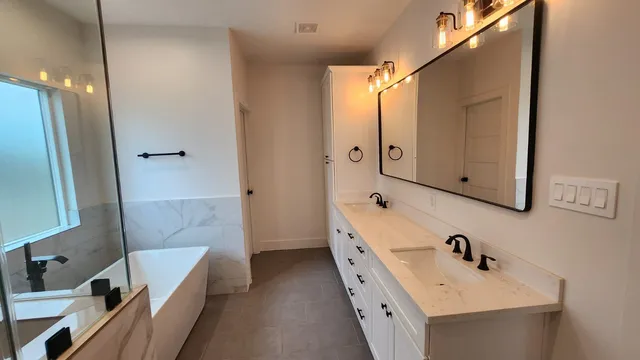a bathroom with a double vanity sink a mirror and a bathtub