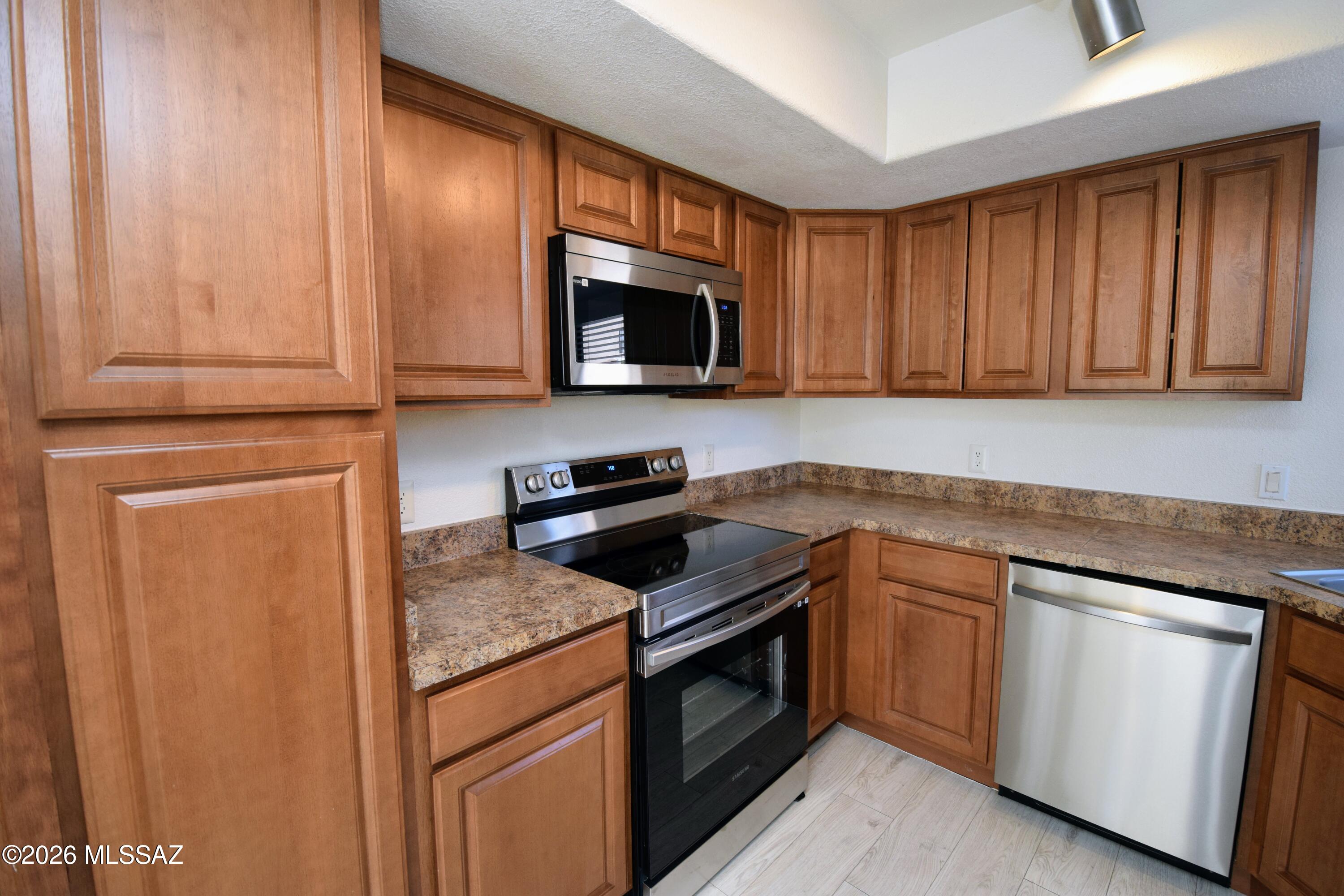 5855 North Kolb Road, Unit 11106 Tucson, AZ 85750 - Photo 12 of 36 a kitchen with granite countertop wooden cabinets and a stove top oven