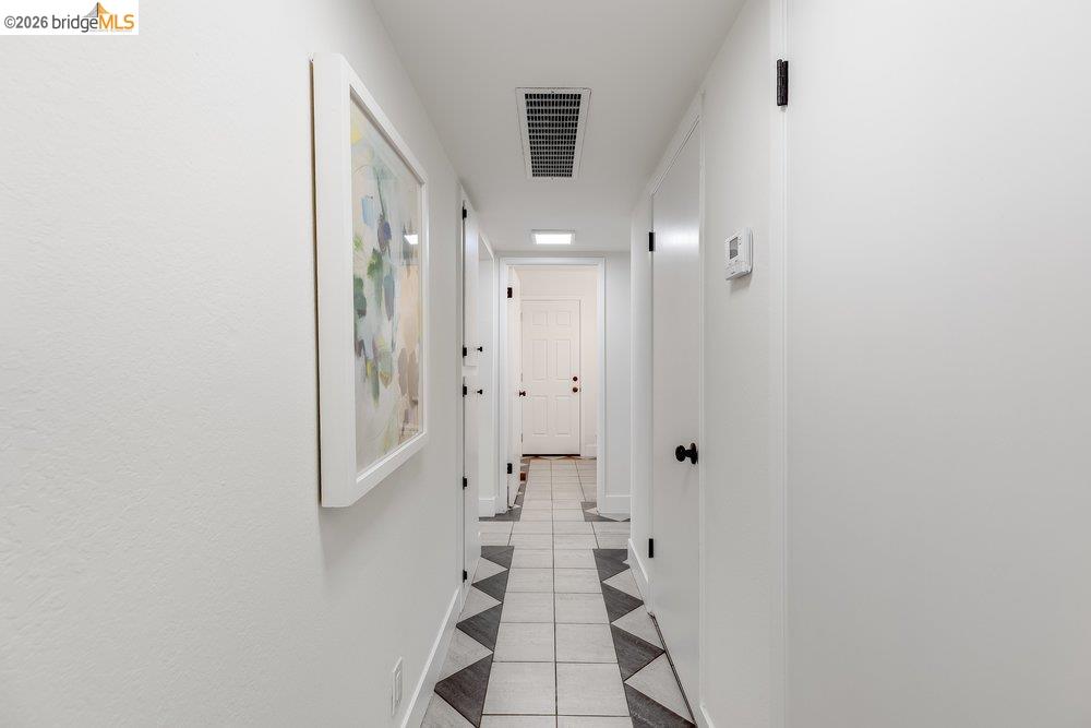 1298 Ribbon Street Foster City, CA 94404 - Photo 39 of 86 Hallway featuring light-toned walls, tile flooring with a geometric pattern, and multiple white doors with matte black hardware