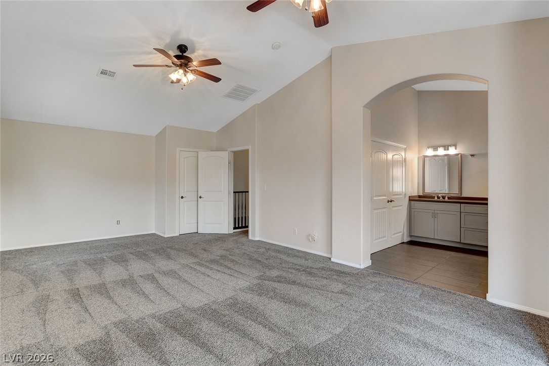 191 Verde Ridge Court Henderson, NV 89012 - Photo 21 of 36 Unfurnished bedroom featuring carpet floors, lofted ceiling, arched walkways, a sink, and ensuite bath