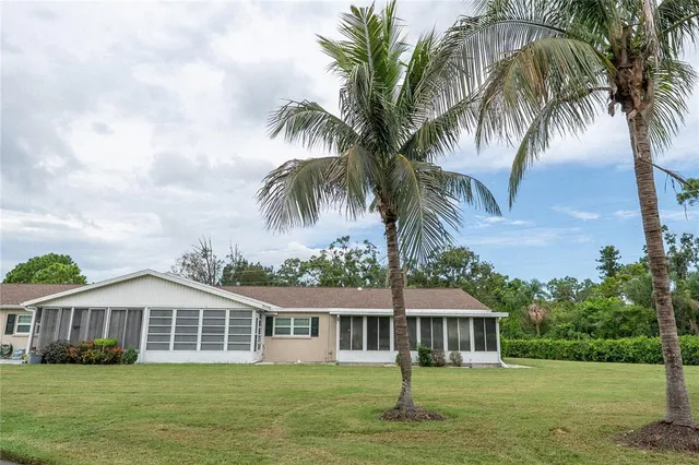 a front view of a house with a garden and palm trees