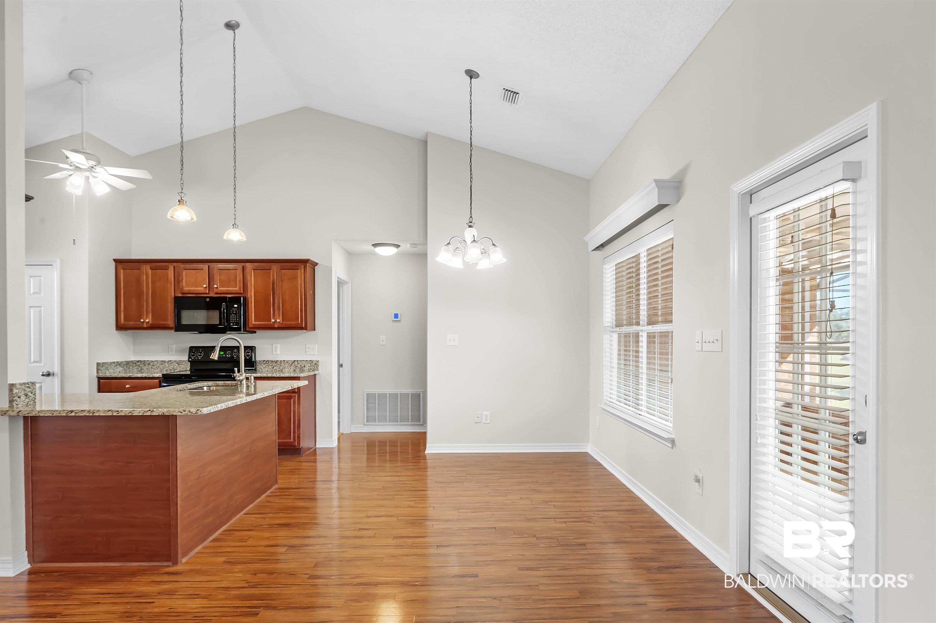 421 Collinwood Loop Foley, AL 36535 - Photo 22 of 62 Kitchen with high vaulted ceiling, wood-type flooring, black appliances, ceiling fan with notable chandelier, and light stone counters