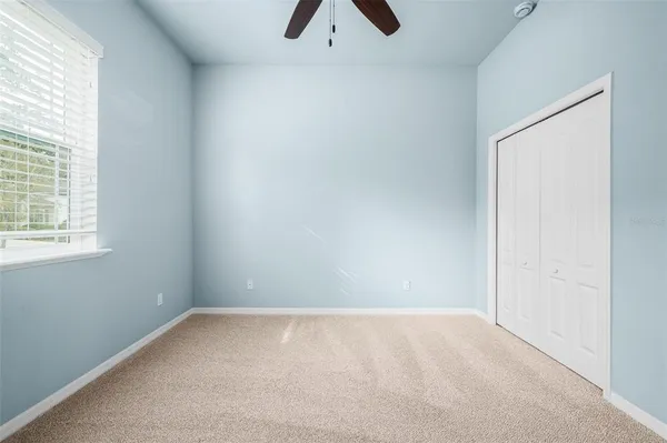 an empty room with a window and a ceiling fan
