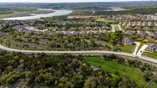 an aerial view of a residential houses with outdoor space and trees
