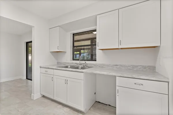 a kitchen with white cabinets appliances a sink and a window
