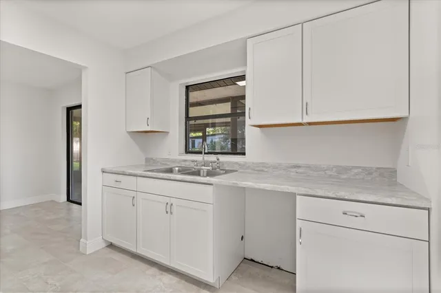 a kitchen with white cabinets appliances a sink and a window