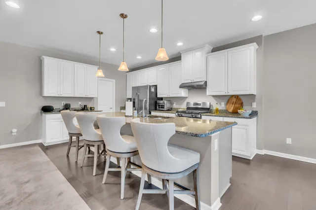 a kitchen with kitchen island granite countertop a dining table chairs and white cabinets